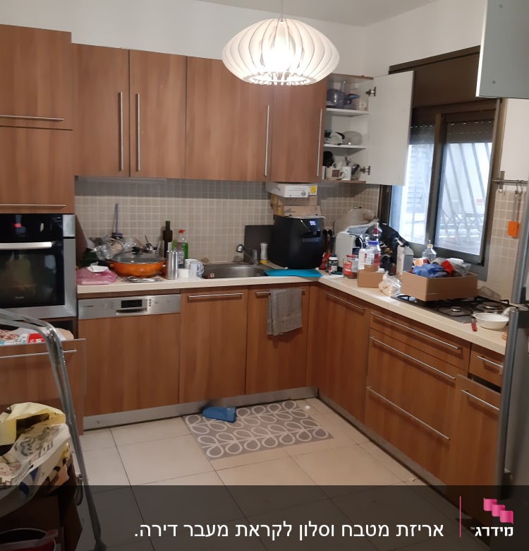 מטבח עם ארונות עץ, כלים על השיש, מקרר עם מגנטים